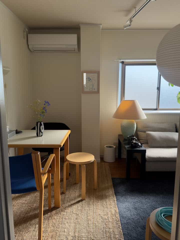 Natural tones and white-walled studio dining room featuring sofa and dining table arranged in cozy, simple modern style