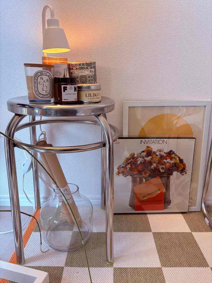 Silver stainless steel stool topped with assorted candles in a living room corner, creating a clean and modern atmosphere