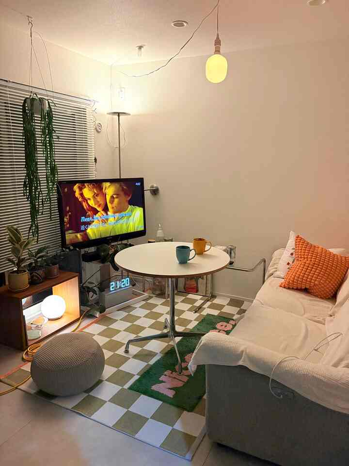 Warmly lit mid-century modern living room featuring a white sofa and round table centered with orange cushions as accents