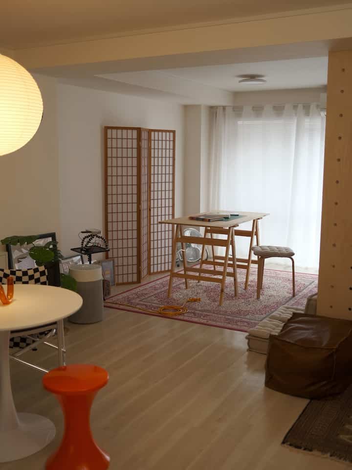 Bright natural-toned long and narrow Wa-Modern living room featuring a wooden table and sheer curtains with a cozy atmosphere