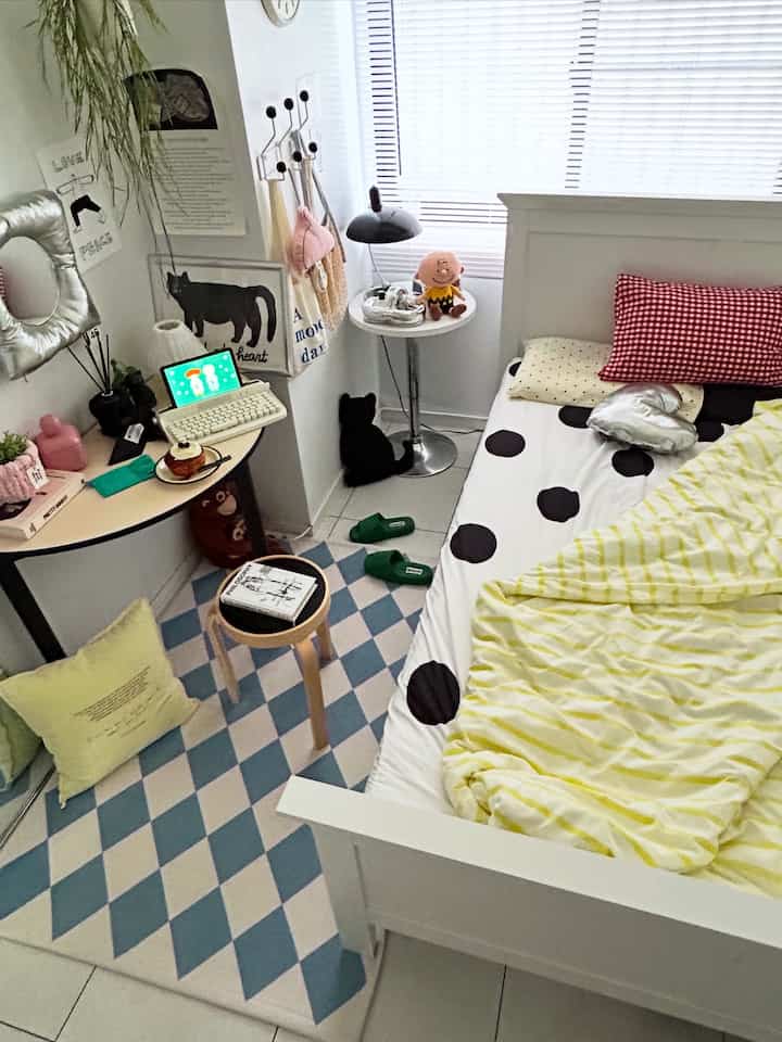 White and blue toned bedroom featuring a checkered rug, bed, small desk, and stool creating a cozy atmosphere