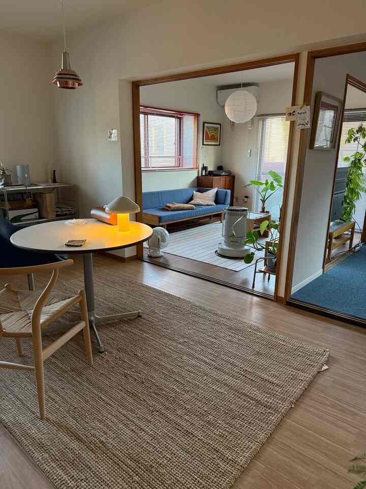 Natural toned two-person household living and dining room featuring blue sofa, beige rug with clean, minimalist design