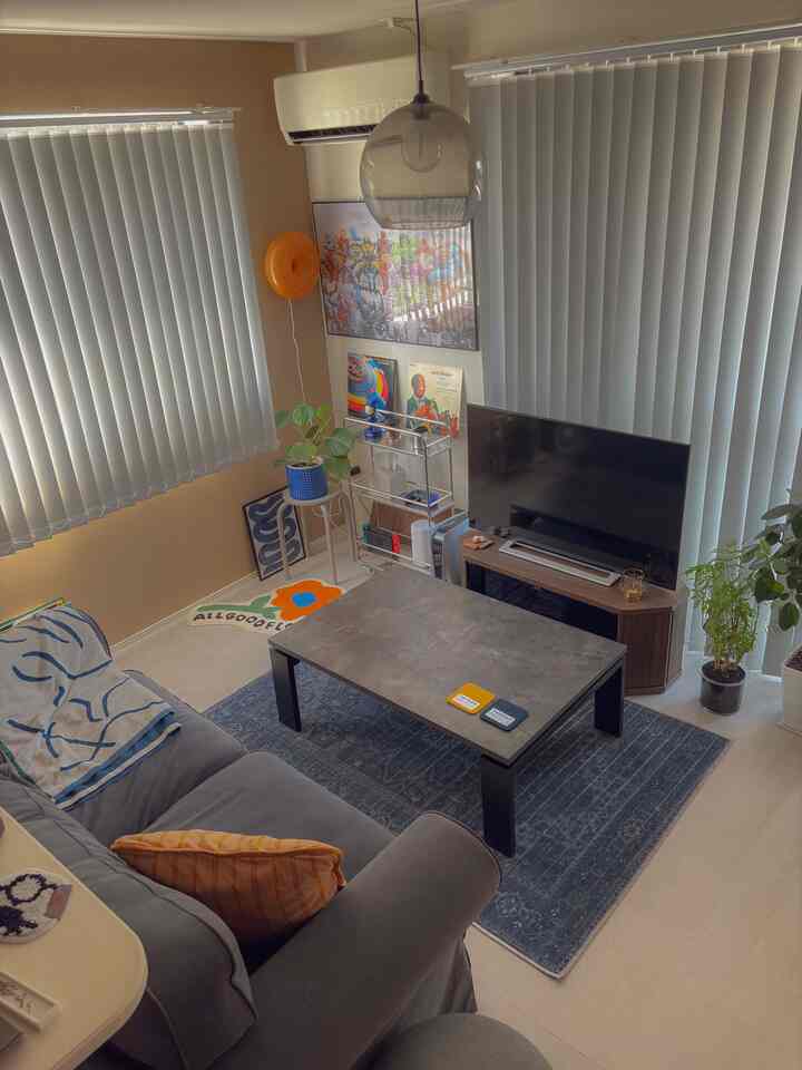 A modern living room with navy and gray tones featuring a sofa, rug, and pendant light