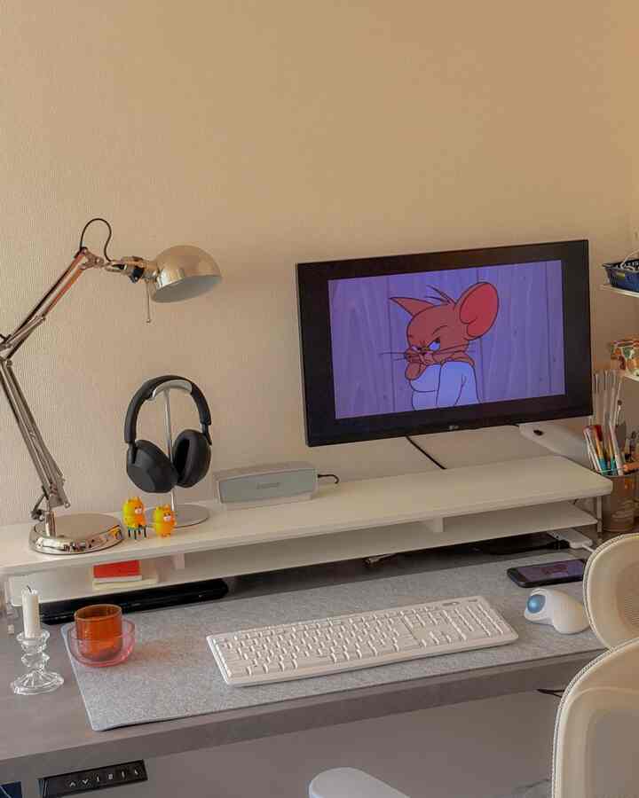 White and silver toned home office featuring a desk, monitor, and desk lamp in a tidy workspace