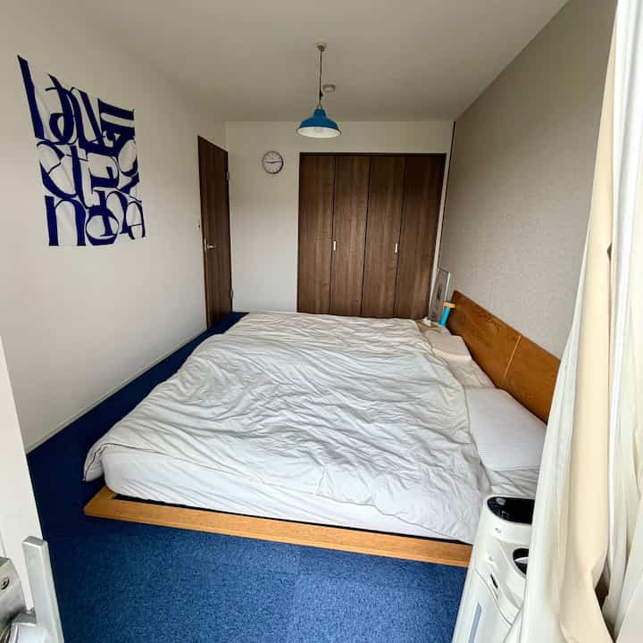 Simple 6-tatami bedroom with blue carpet and natural wood bed frame