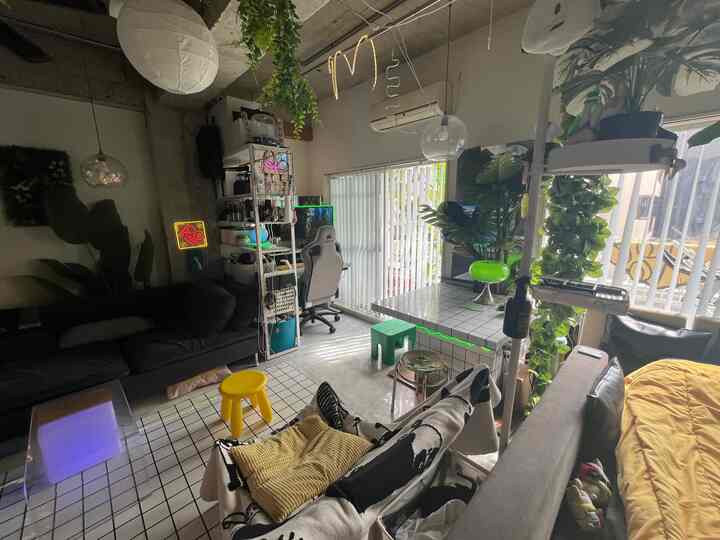 Modern wide studio apartment living room featuring black sofa, white furniture, and green plants with practical atmosphere