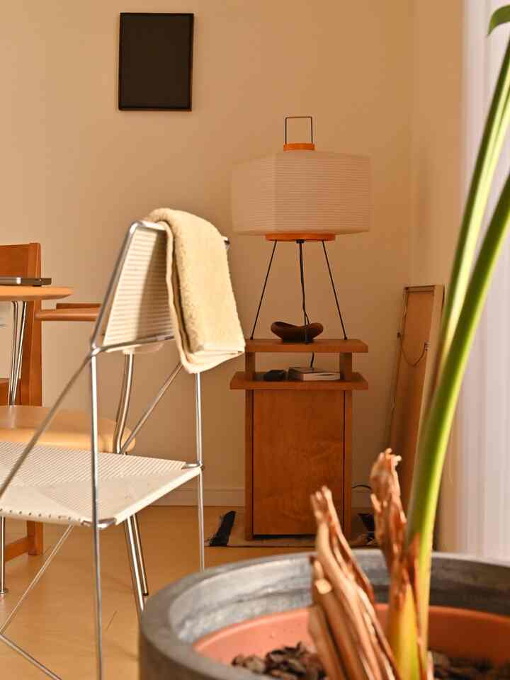 Natural tone living room with beige walls, wooden side table featuring a table lamp and towel draped over chair