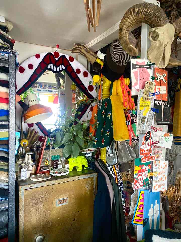 Vintage-inspired wall decor space featuring various objets, a sheep skull replica, colorful bags, and wall posters