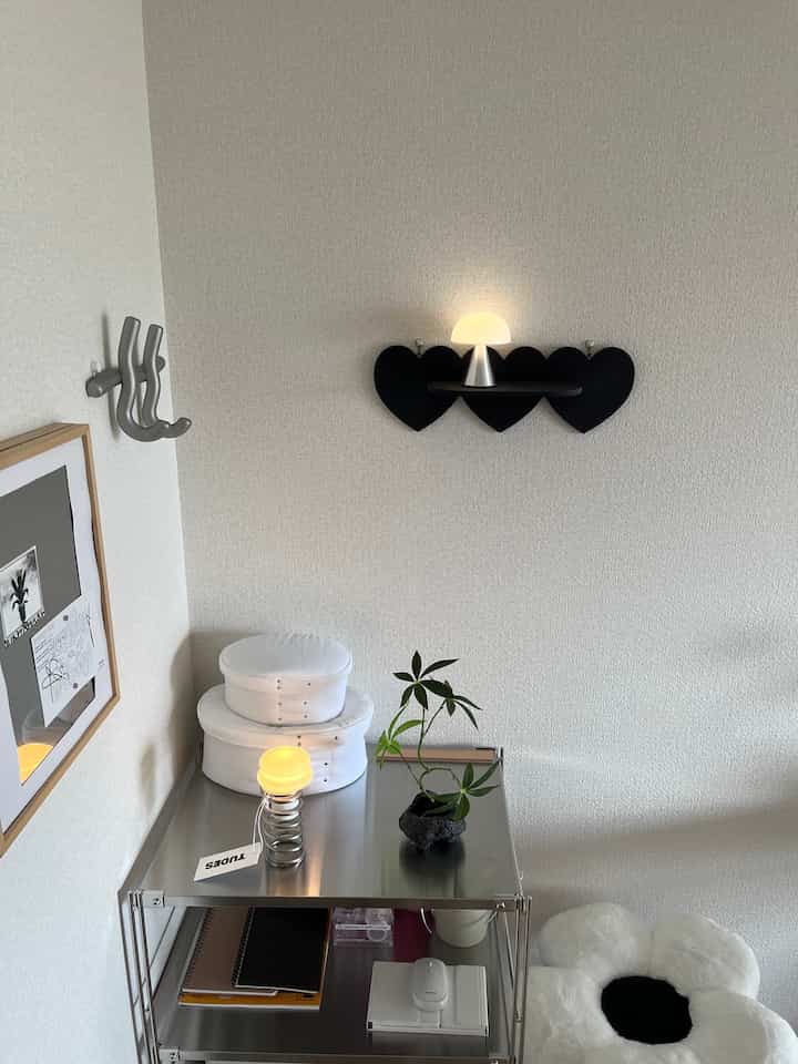 Silver and white toned 1LDK space featuring a metal desk, flower-shaped cushion, and table lamps with a simple modern vibe