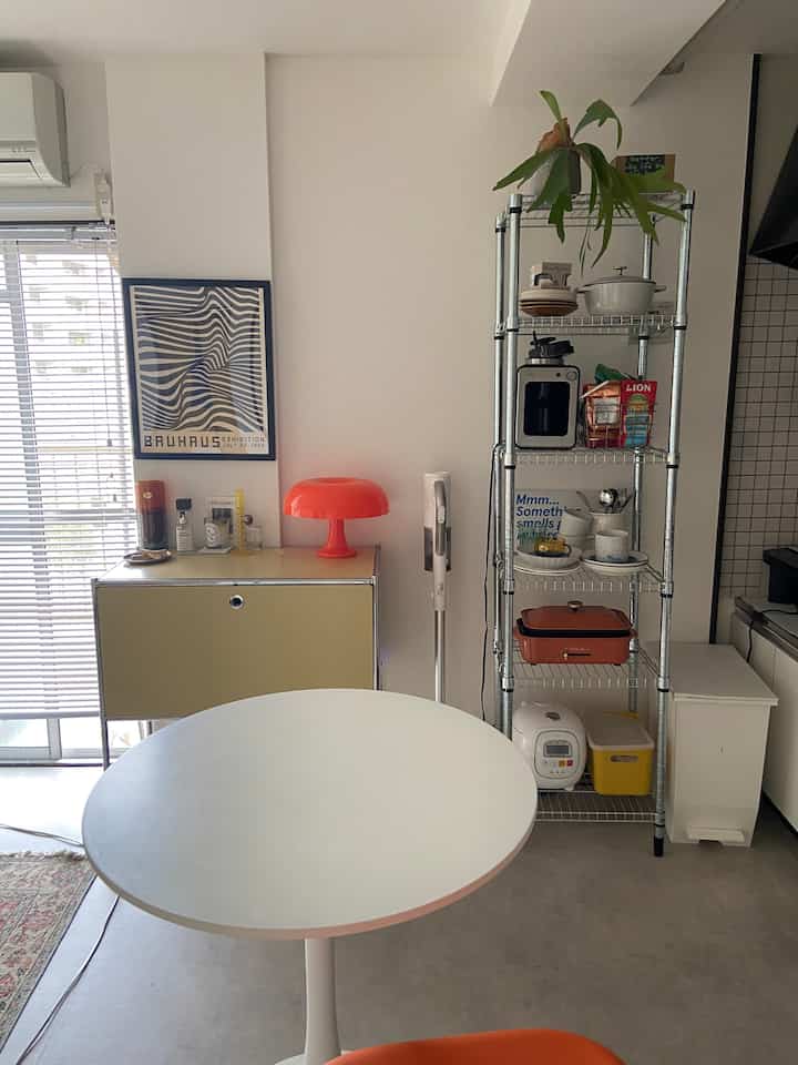 White and orange accented 1DK kitchen space featuring shelving and lamps creating a Mid-Century Modern vibe