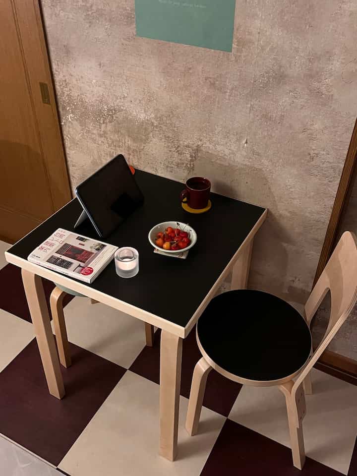 A calm Mid-Century Modern home cafe space with black tabletop and wood-tone desk arranged for single household use