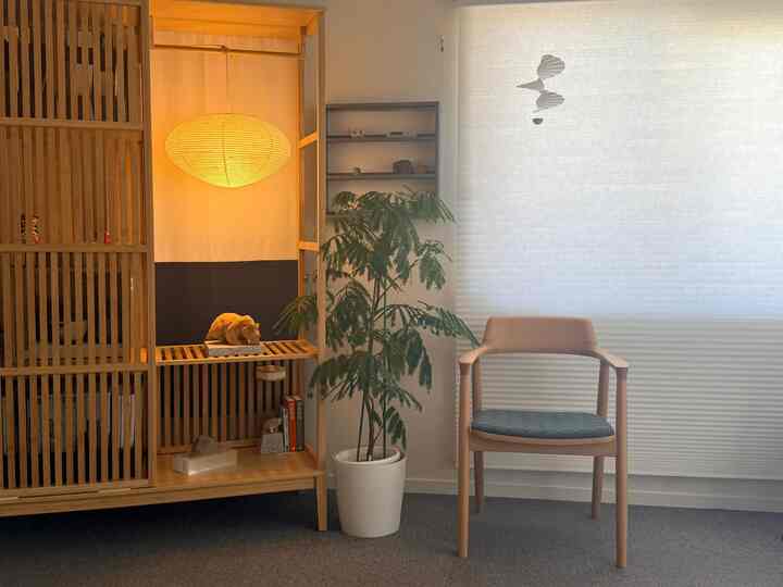 Natural wood tone living room featuring a wooden armchair, green plant, and warm pendant light creating a cozy atmosphere