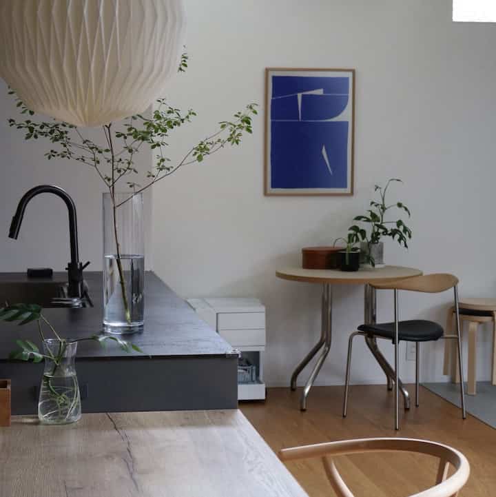 Wood tone and black kitchen with a small cafe-style dining room, white walls and a blue poster combine for a neat atmosphere