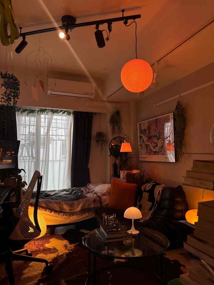 Warm orange-lit small studio living room with brown tones, featuring sofa and table lamp creating a cozy atmosphere