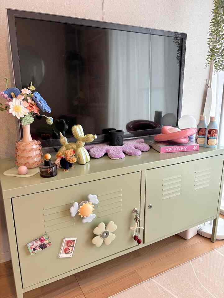 Soft green cabinet topped with decorative objects and large TV, creating a cozy living space for baby and pet coexistence