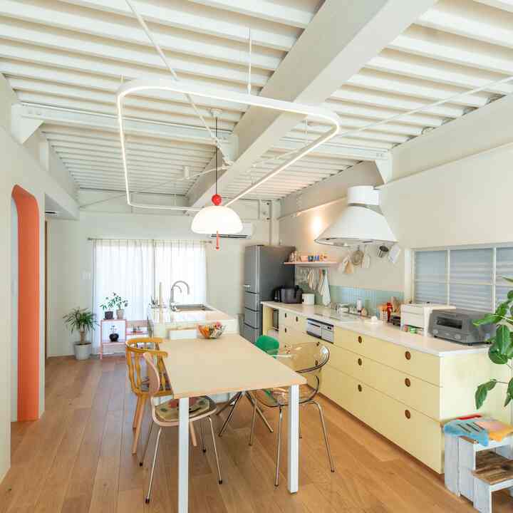 Bright white and natural wood-tone kitchen and dining room featuring pastel yellow cabinets and diverse chairs in a vibrant space
