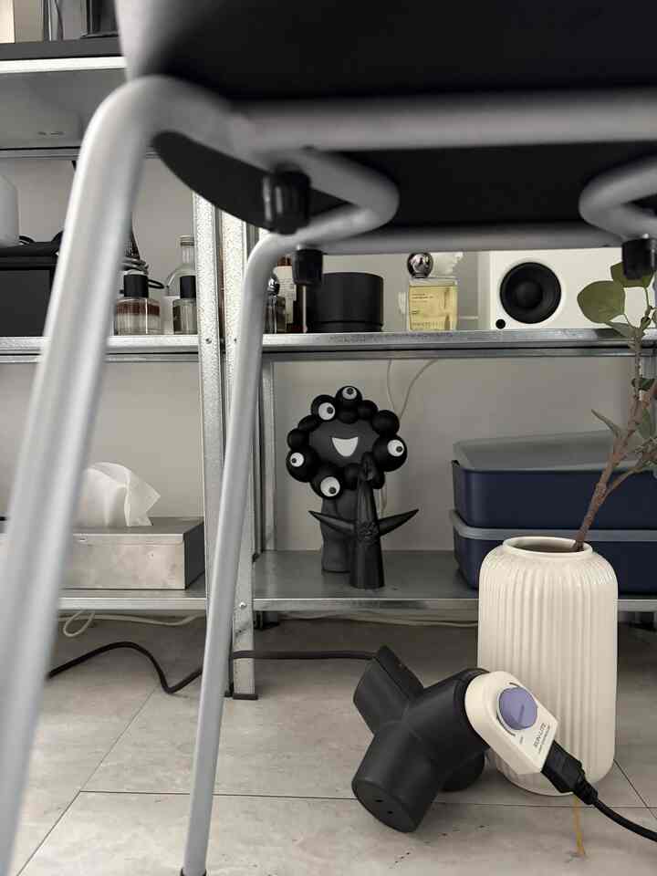 Modern white-toned small indoor space featuring metal shelving and a black stool in the foreground