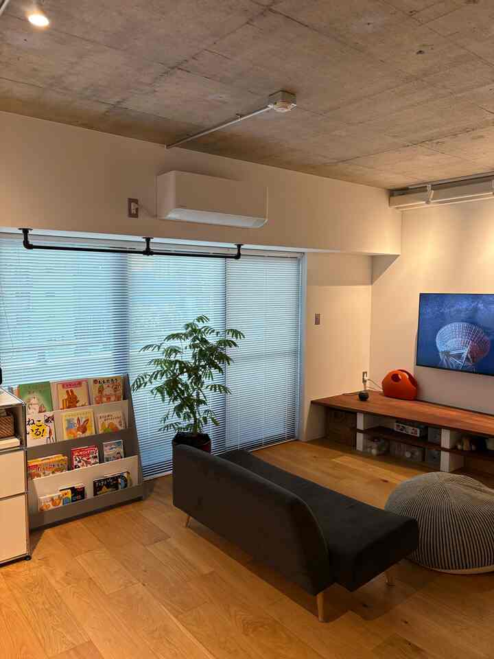 ナチュラルな木目調と白い壁のリビング、子供用の本棚が配置された雰囲気のある空間