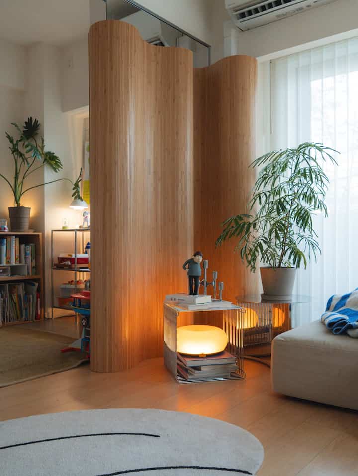 Natural wood tone room divider featuring plants separating a cozy living room and kids' room space