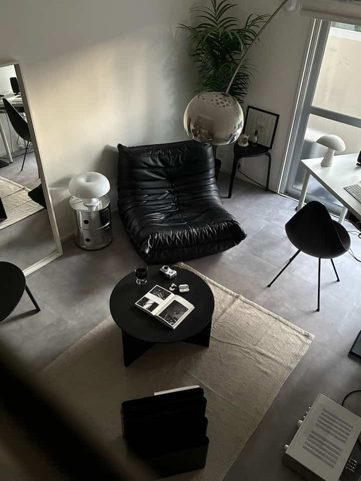 Monotone single household living room featuring a black sofa and side tables with a simple modern interior