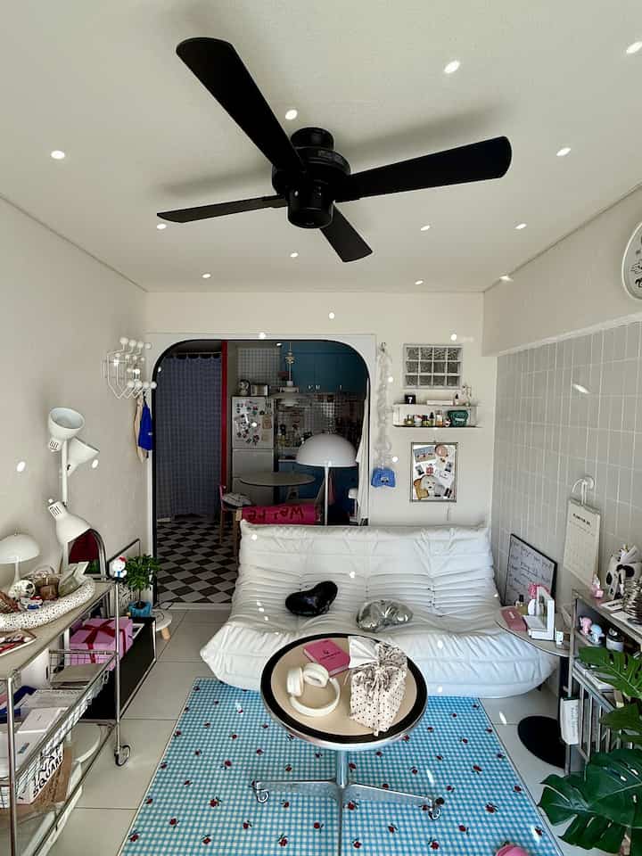 White and black toned living room connected to kitchen, featuring mid-century modern sofa and coffee table in a cozy space