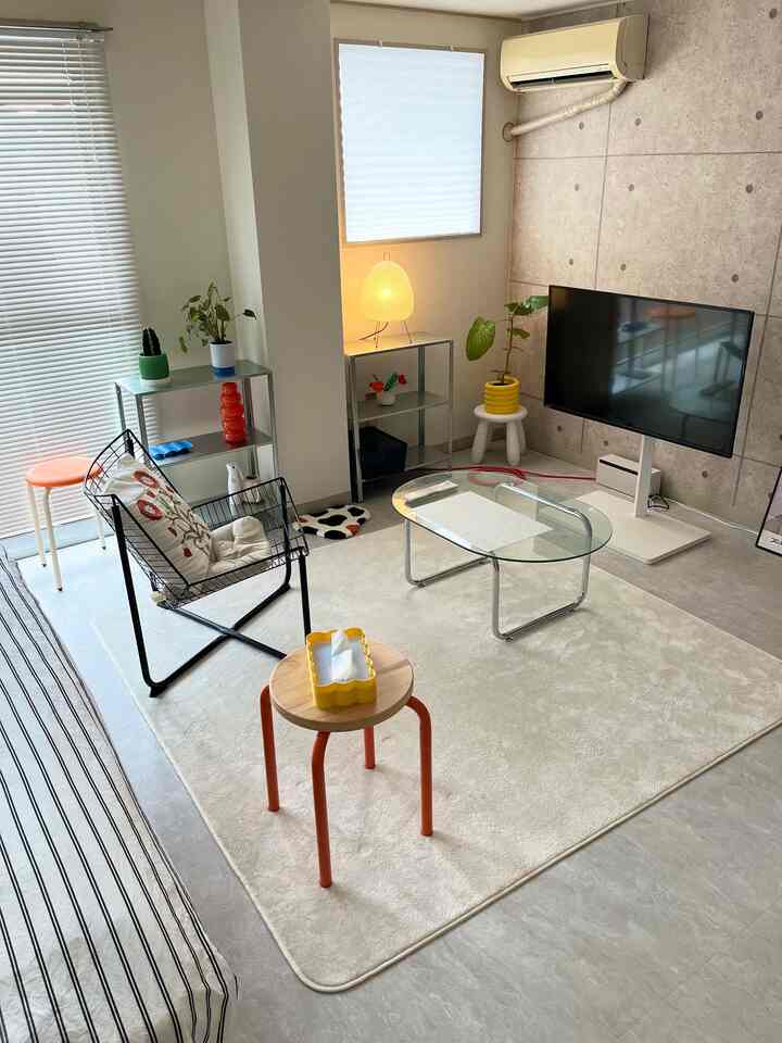 White and modern toned living room featuring blinds, stools, and glass table with a simple and minimal atmosphere