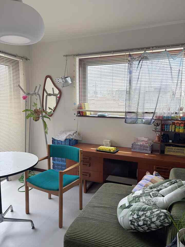 Natural wood tones and green hues in a living room featuring mid-century modern desk and sofa in a cozy setting