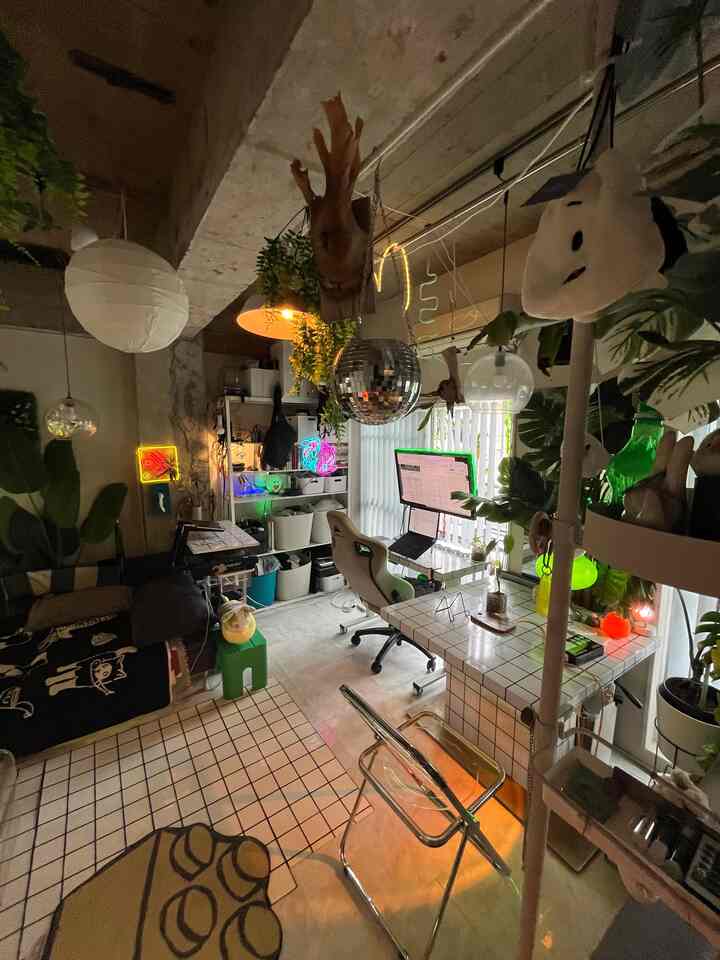 ブラックとグレーが基調の狭いインダストリアルなコンパクトホームオフィス、多くの植物とモダンな家具が配置された印象的な空間