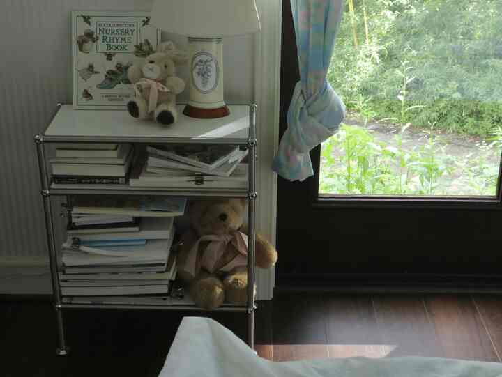 白と茶色のトーンの寝室の隅に配置された本棚と可愛らしいぬいぐるみが置かれた雰囲気のある空間