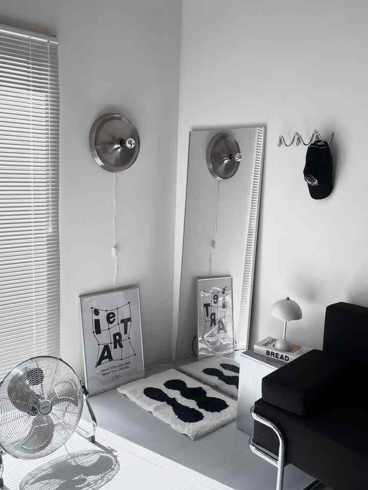 White and black monotone mid-century modern living room featuring a simple sofa, rug, and floor fan with clean, minimalist layout