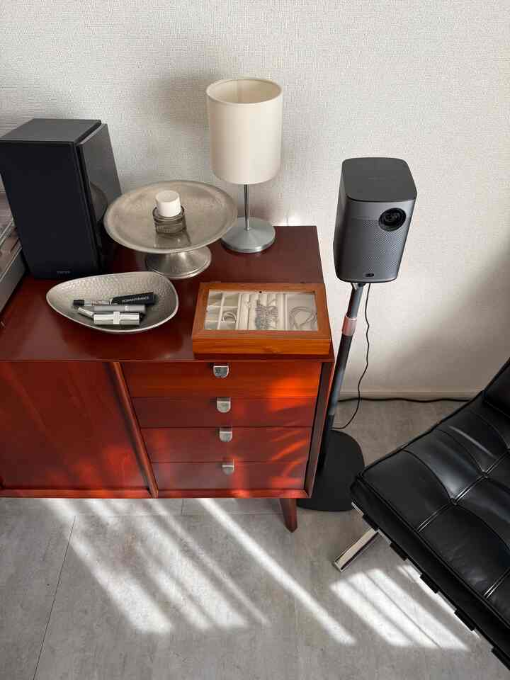 Modern corner space featuring a brown cabinet topped with silver trays, a floor lamp, and black speaker