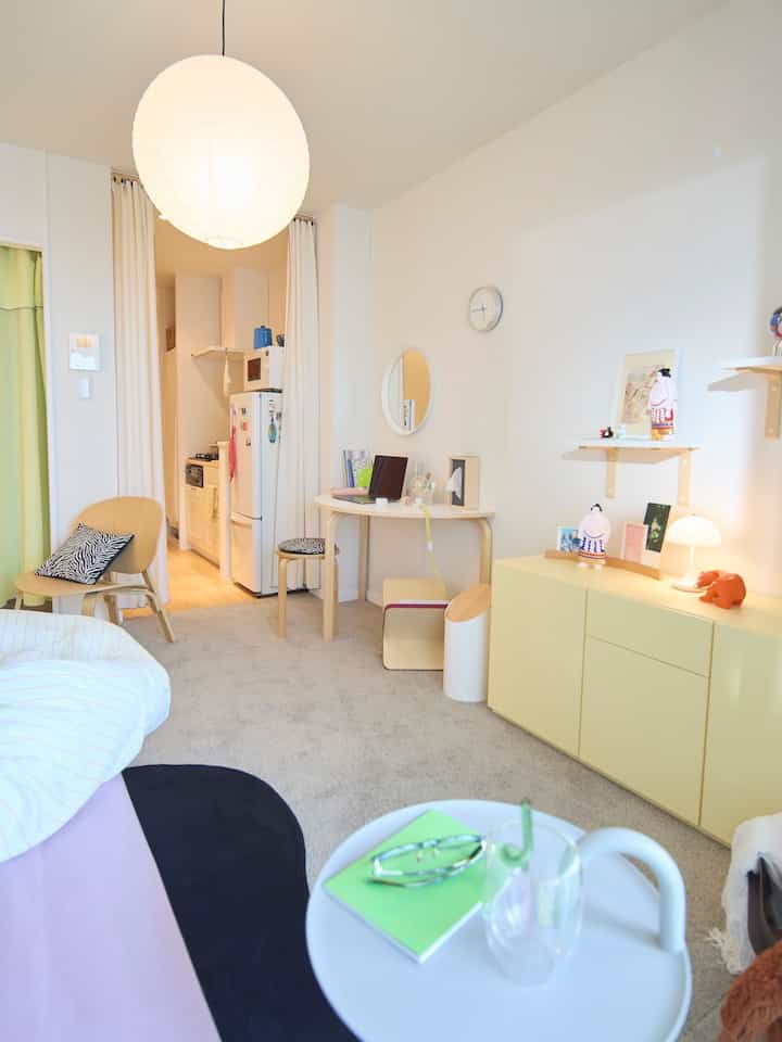 Ivory and white toned studio bedroom and kitchen space featuring natural modern furniture with simple, cozy interior design