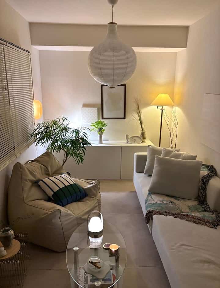 Beige and white toned living room featuring a beige bean bag, white sofa, pendant light, and floor lamp creating a warm atmosphere