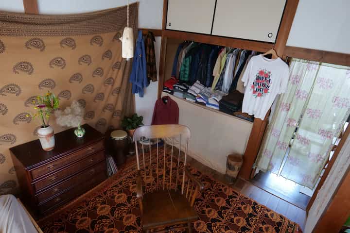 Calm brown-toned Bohemian bedroom featuring vintage rug, wooden chair, and visible clothing closet in a cozy setting