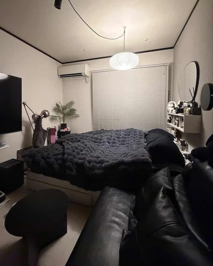 Modern 1K bedroom with white and black tones featuring a large bed, sofa, and pendant light, creating a cozy atmosphere