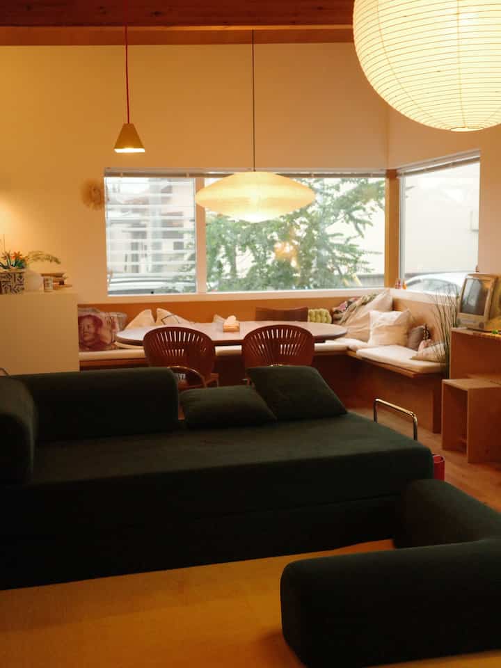Navy and wood toned living and dining room featuring large windows and pendant lights with a cozy atmosphere