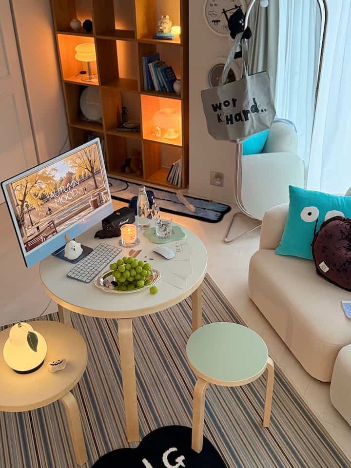 White and wood-toned studio home office with bookshelf, sofa, and Halloween decorations creating a cozy interior