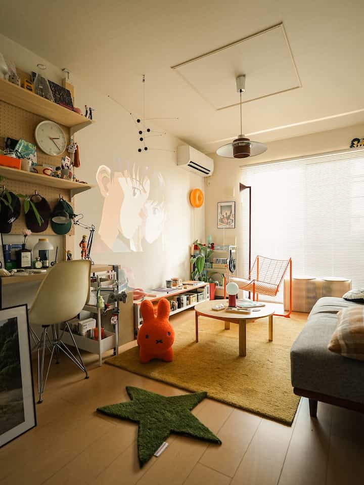 黄色いラグとグレーのソファがある、カラフルでミッドセンチュリーモダンな雰囲気の1LDKリビング