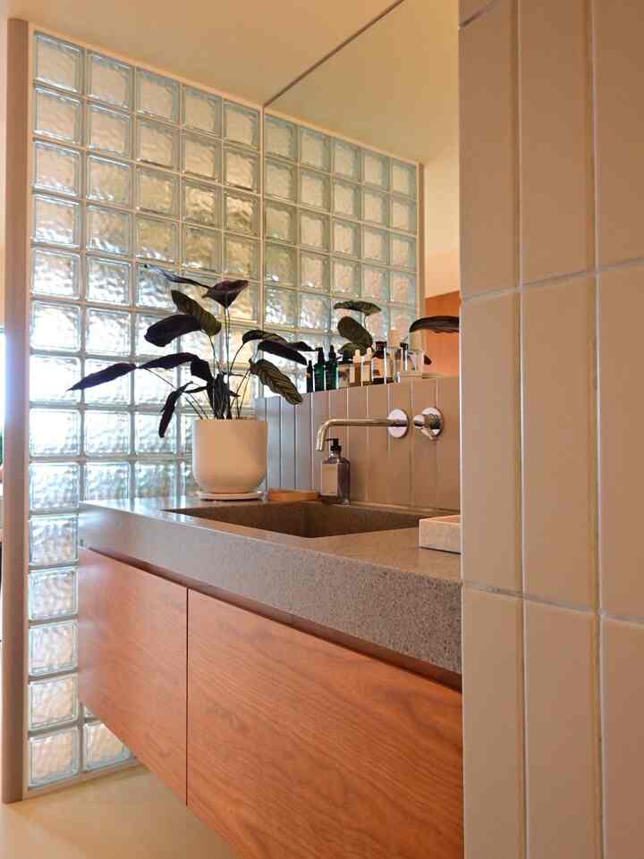 Natural wood-tone bathroom washbasin area with a glass block wall creating calm ambiance