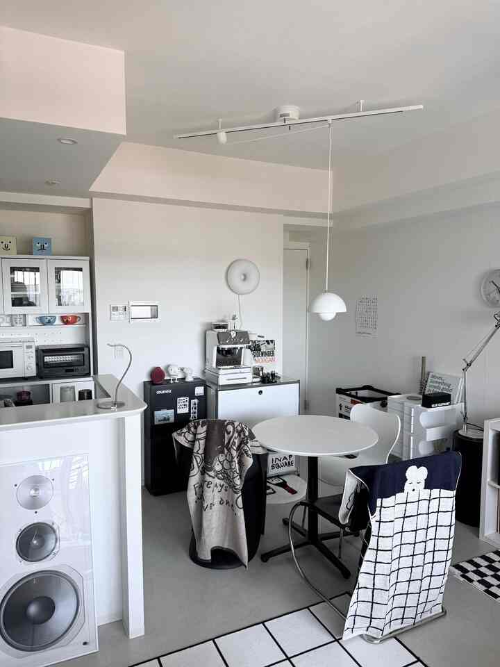A monotone and white-toned dining room featuring a round dining table and pendant light with a simple atmosphere