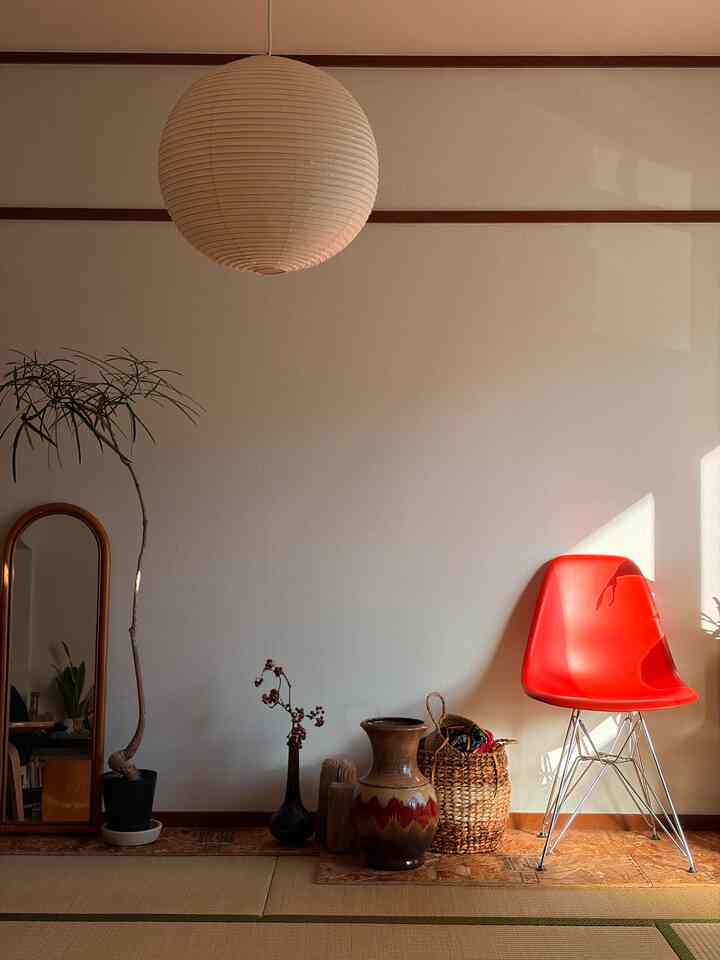 Beige wall with wooden accents featuring a red chair and pendant light in a simple, natural interior