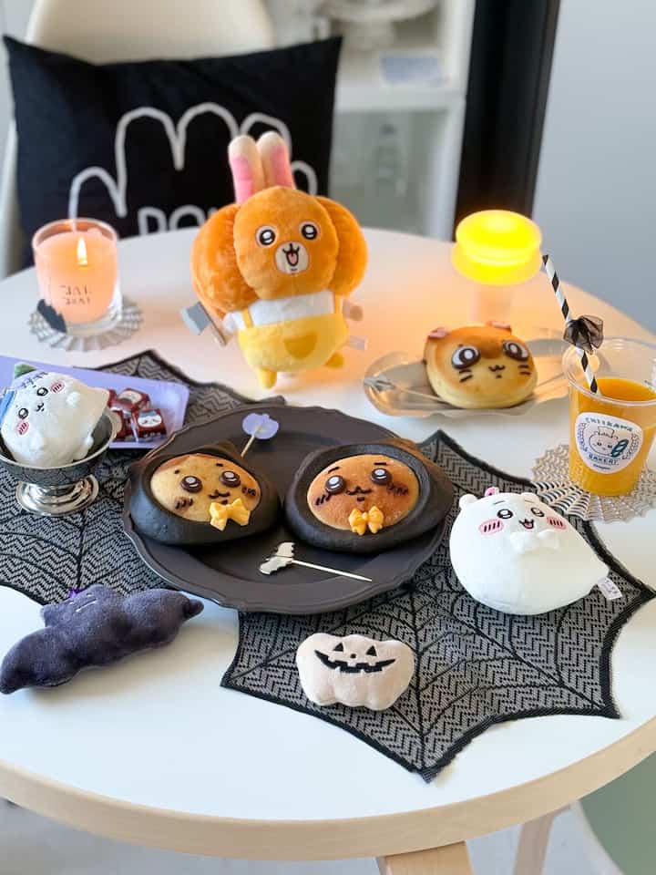 A white round dining table with a black lace table runner featuring cute Halloween-themed character breads and decor in a Korean interior style home cafe