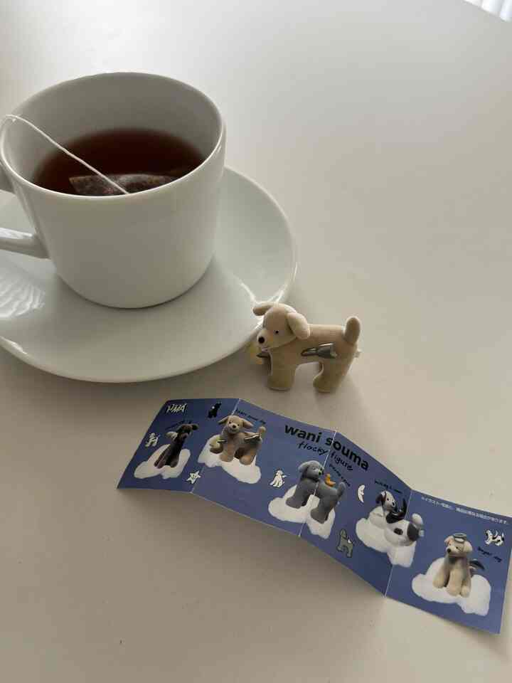 白を基調としたテーブルの上にマグカップと小さな犬のフィギュアが置かれたシンプルな空間