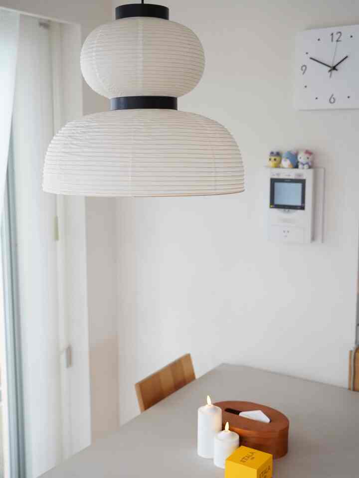 White tone dining room featuring wooden chair, lit candles on table, and pendant light creating a simple atmosphere