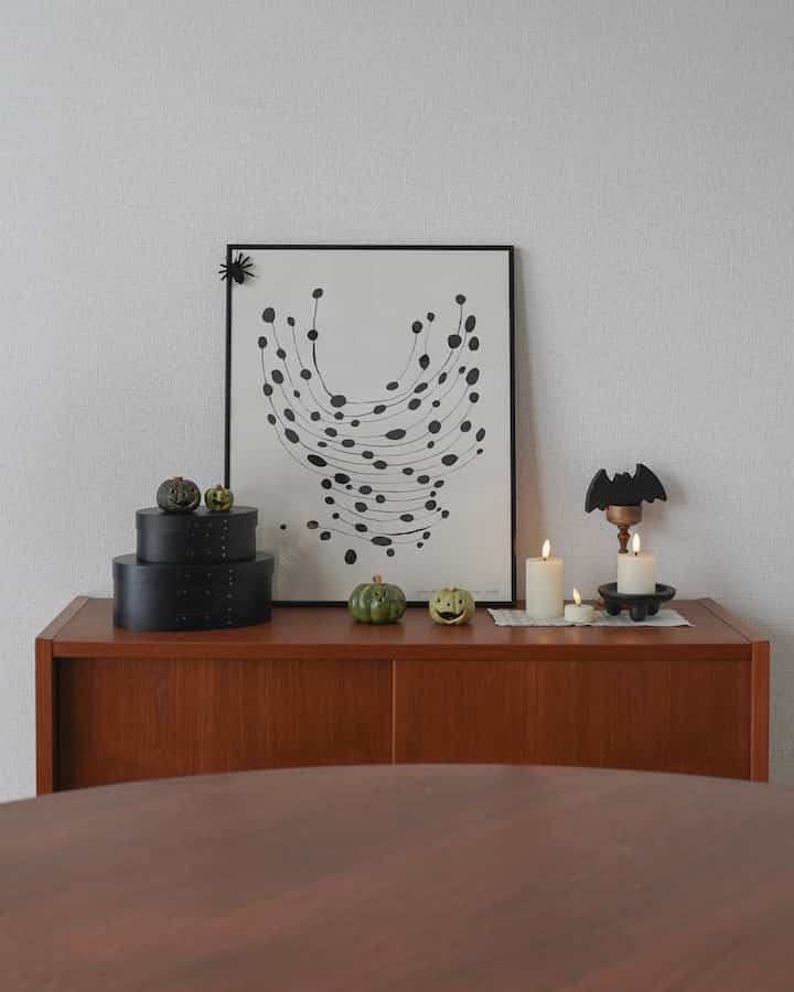 Nordic vintage style dining room with green and black Halloween decorations and candles arranged on the sideboard