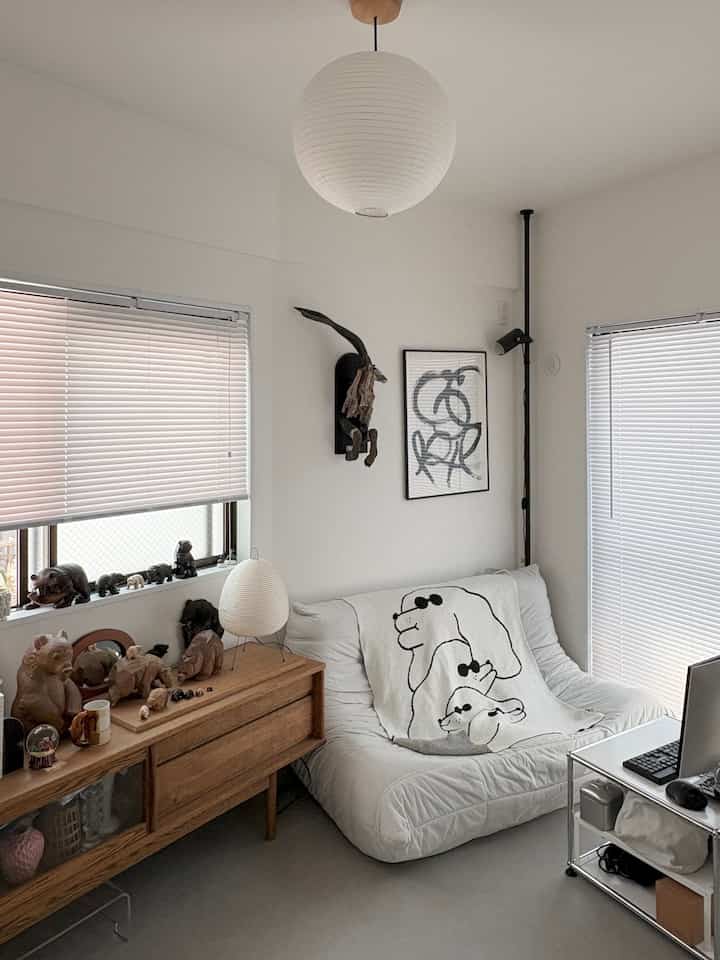 White and wood-tone Japandi living room featuring a sofa, sideboard, pendant light, and minimalist decor creating a clean atmosphere