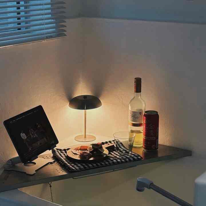 白を基調とした狭いバスルームにテーブルランプとおうちカフェの飲み物が配置された雰囲気のあるインテリア