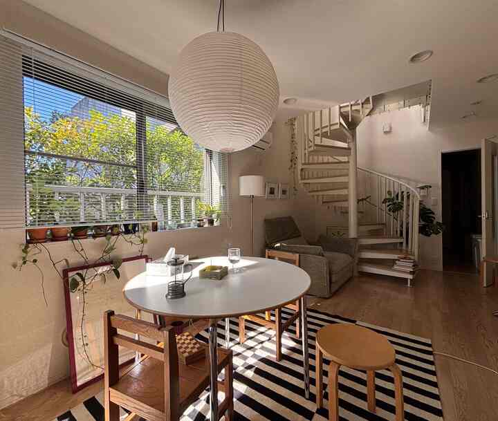 White and brown toned living and dining room featuring round dining table and spiral staircase with a natural atmosphere