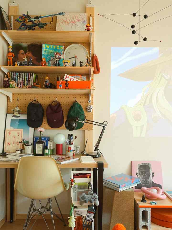 ナチュラルカラーと木製棚が特徴のコンパクトなホームオフィス、さまざまなフィギュアとミッドセンチュリーモダンの家具が配された雰囲気のある書斎