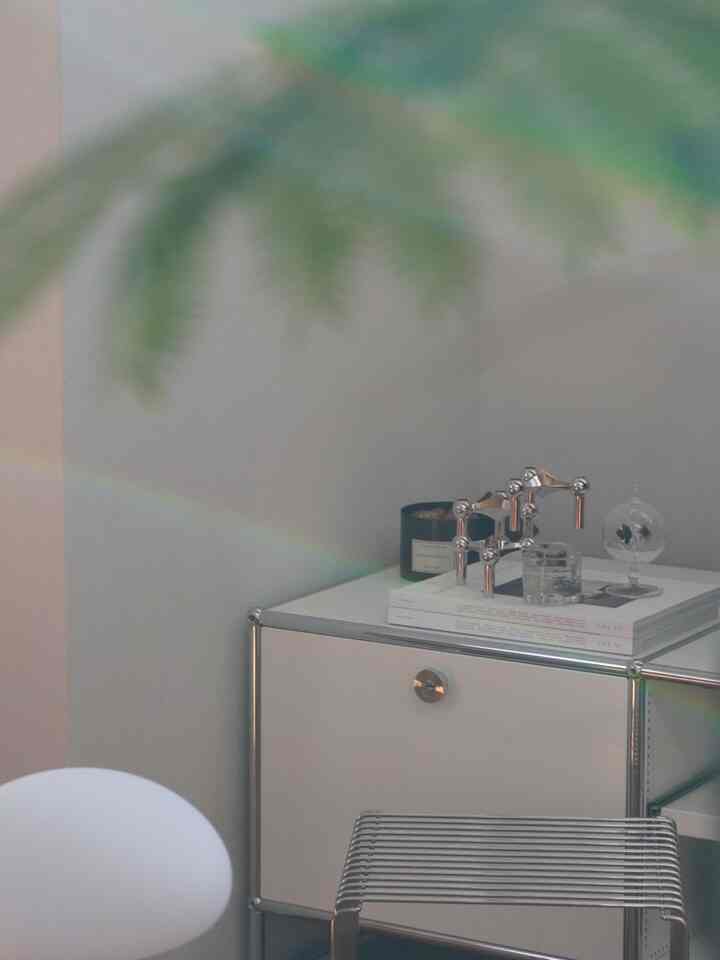 Small modern space in white and silver tones featuring objets and a USM Haller cabinet on the right, clean minimalist interior